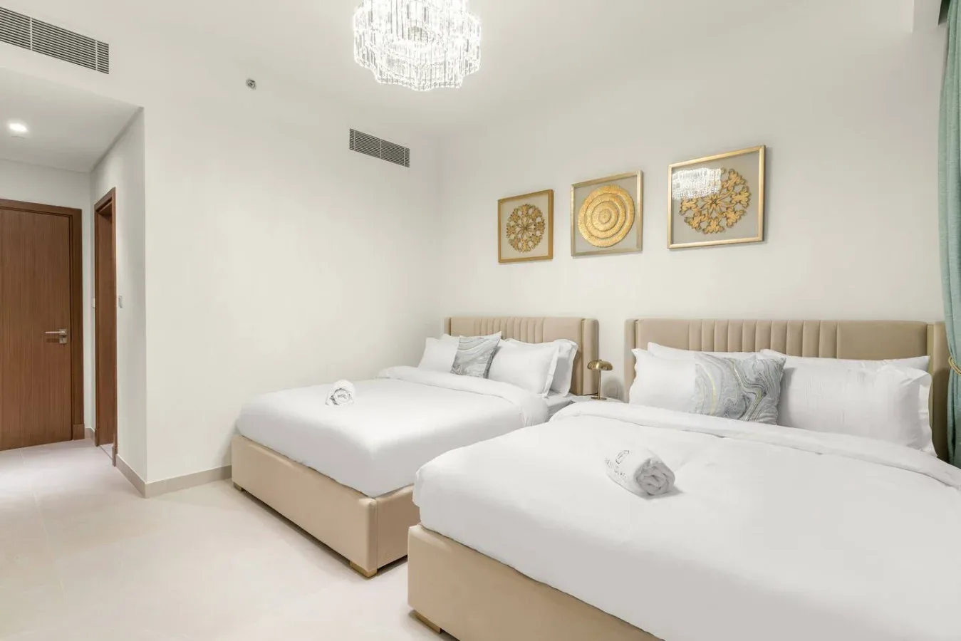 A bright bedroom with two beds and framed artwork above the headboards.