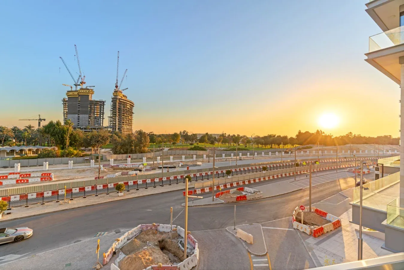 A road construction site stretches across the foreground beneath the setting sun.
