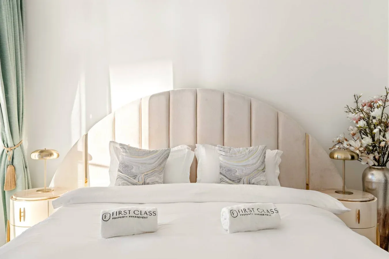 Bedroom with a neatly made bed, upholstered headboard, and matching bedside tables.
