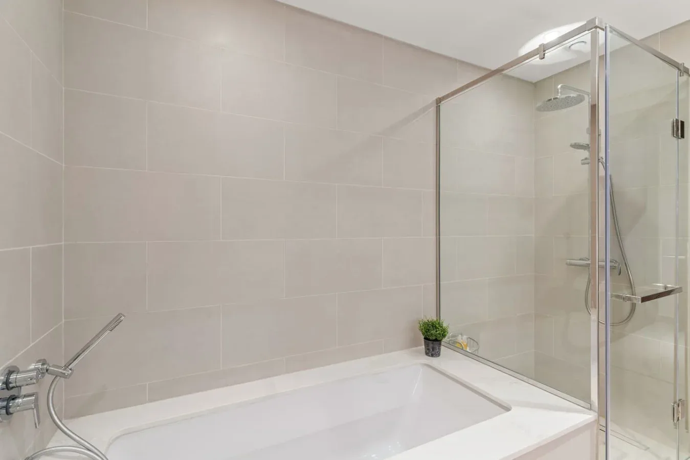A tiled bathroom with a bathtub and glass-enclosed shower.