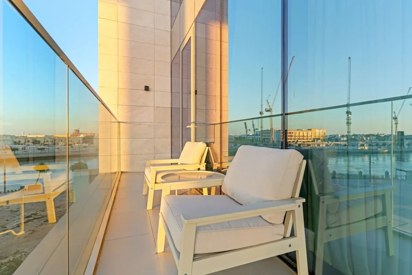 A balcony seating area with lounge chairs and glass railings overlooking the water.
