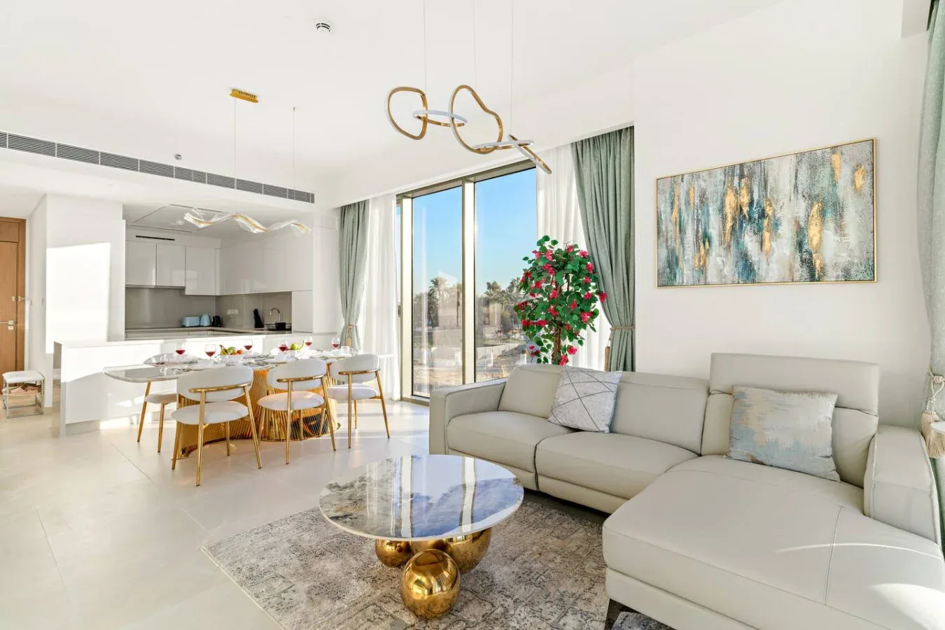 A bright open-plan living and dining area with a sectional sofa and large windows.