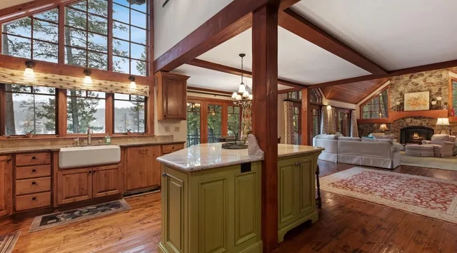 A spacious open-plan living room and kitchen with timber beams and large windows.