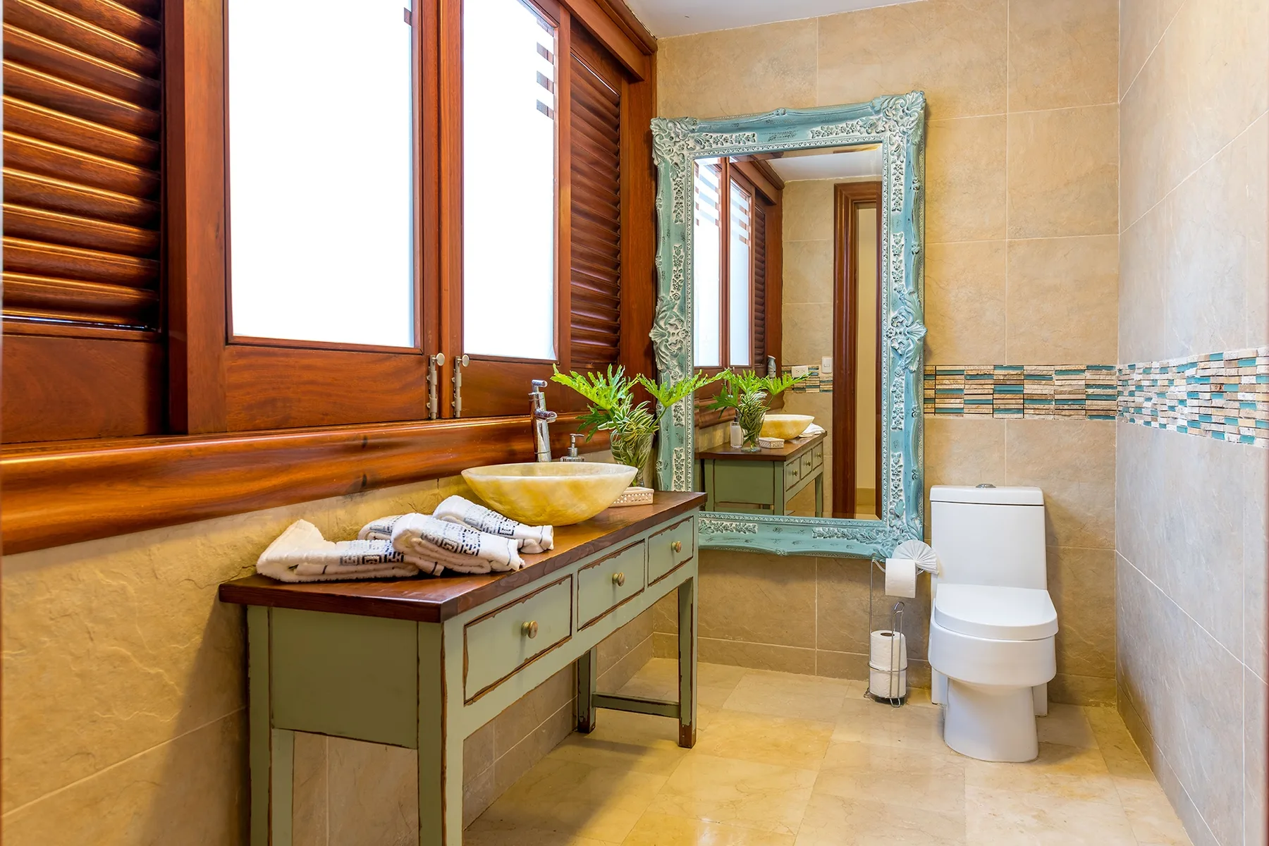 Un baño con tocador, espejo e inodoro.