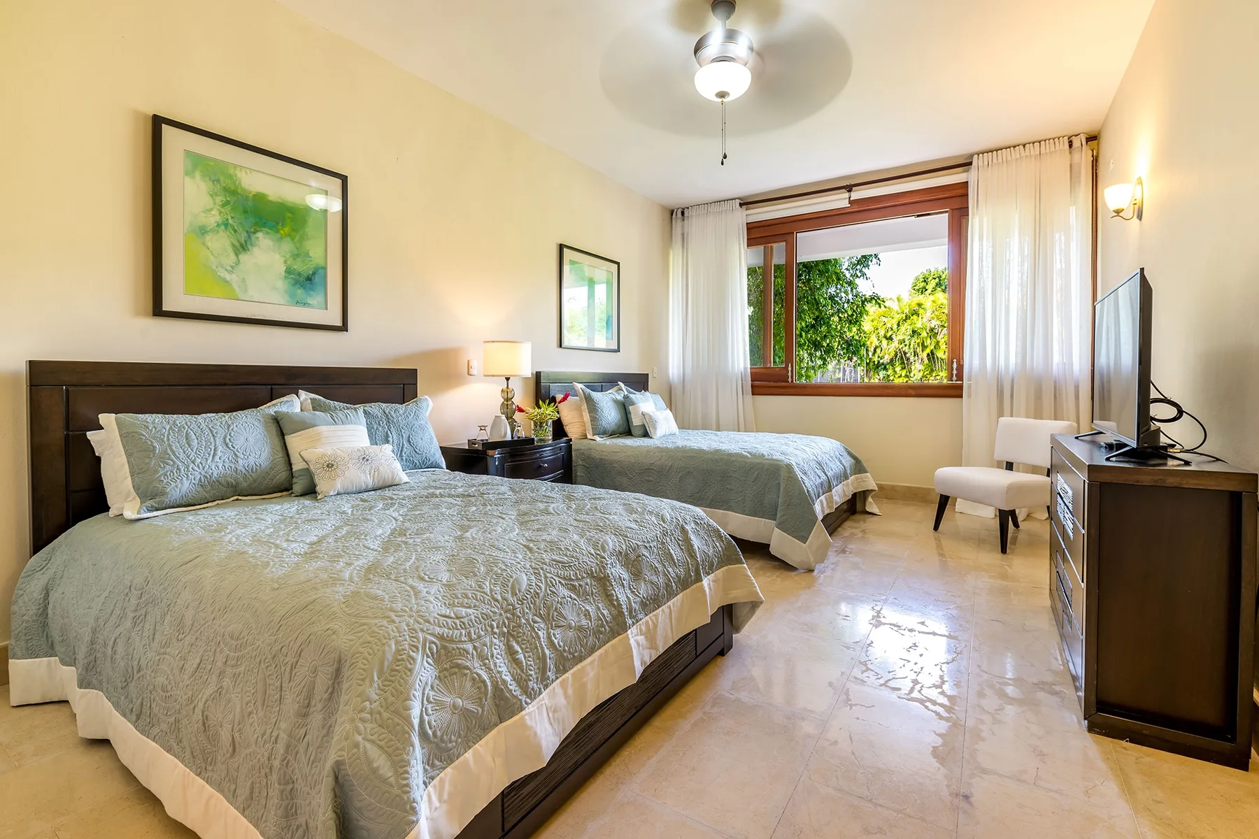 Un dormitorio con dos camas, una ventana y cuadros enmarcados.