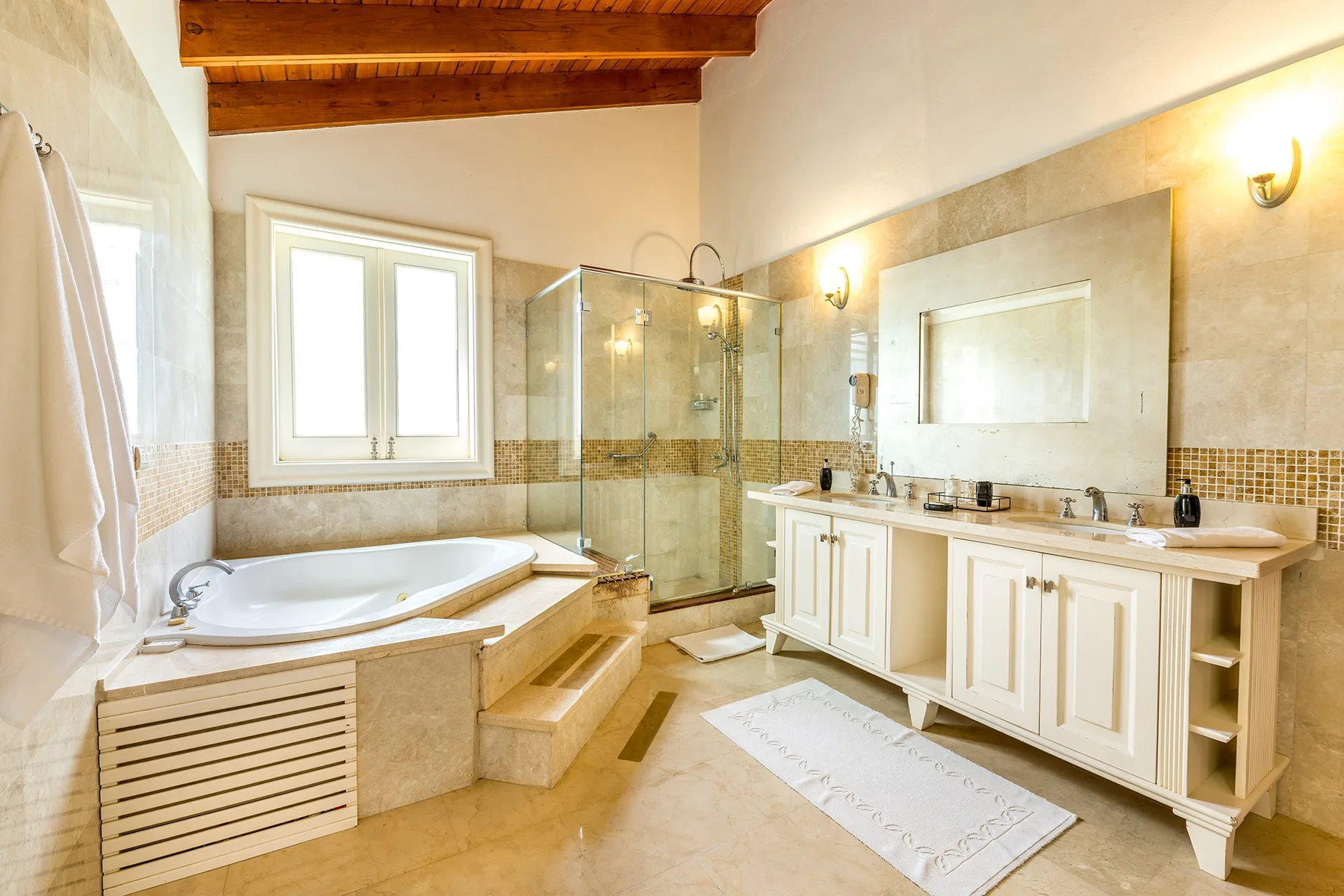 Un baño luminoso con bañera, ducha de vidrio y lavabo doble.