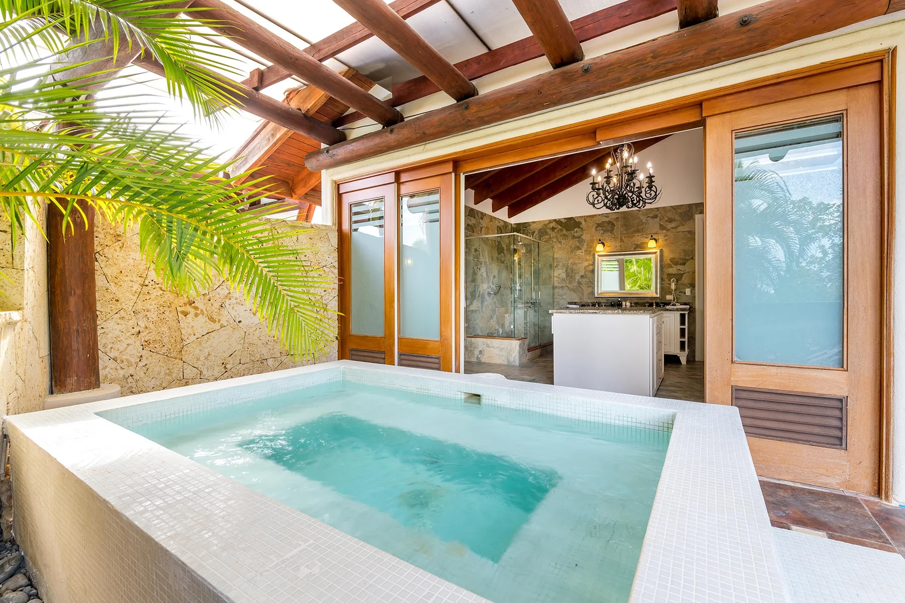 Una piscina pequeña con azulejos está frente a una cocina interior abierta.