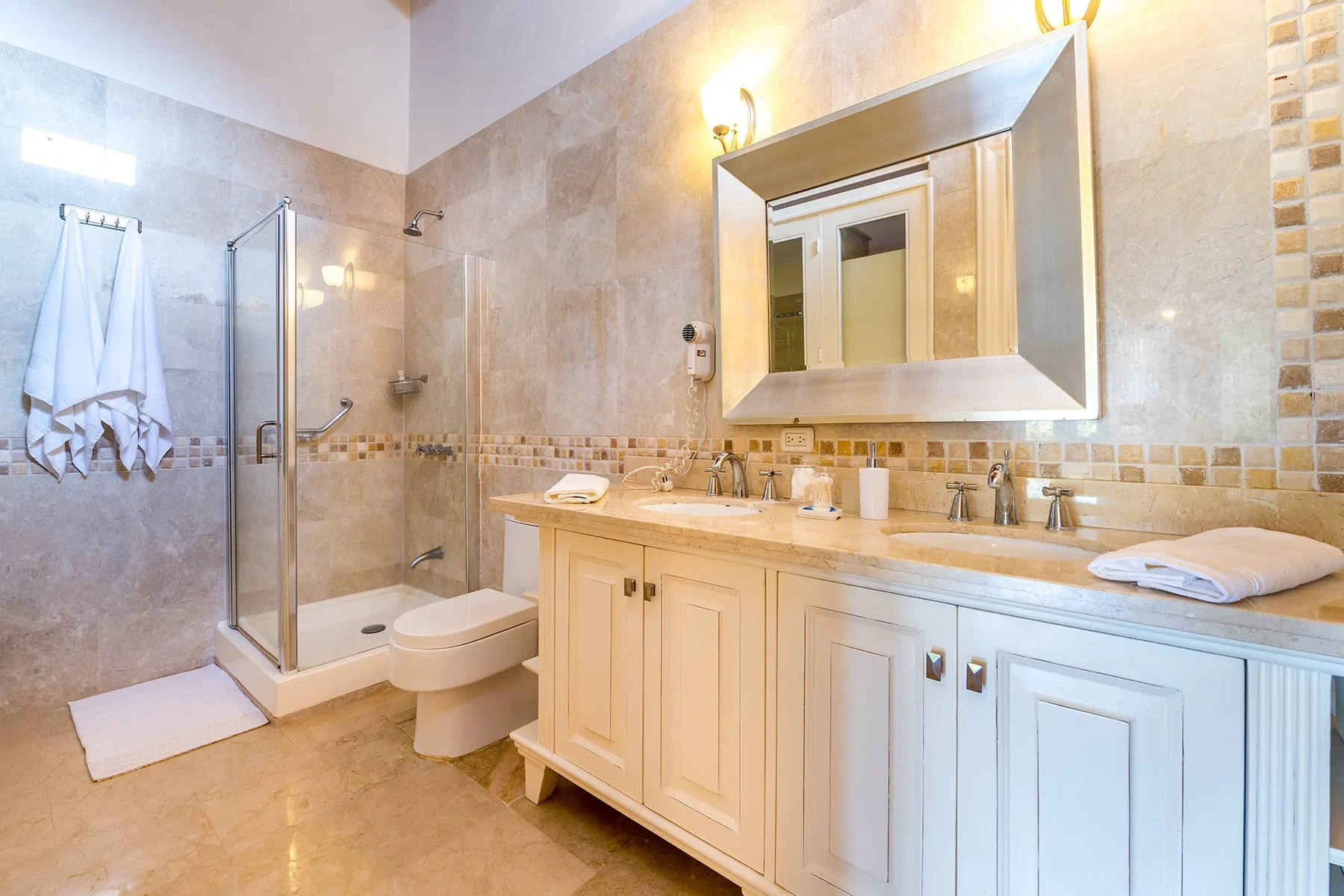 Un baño con azulejos, ducha de vidrio, inodoro y lavabo.