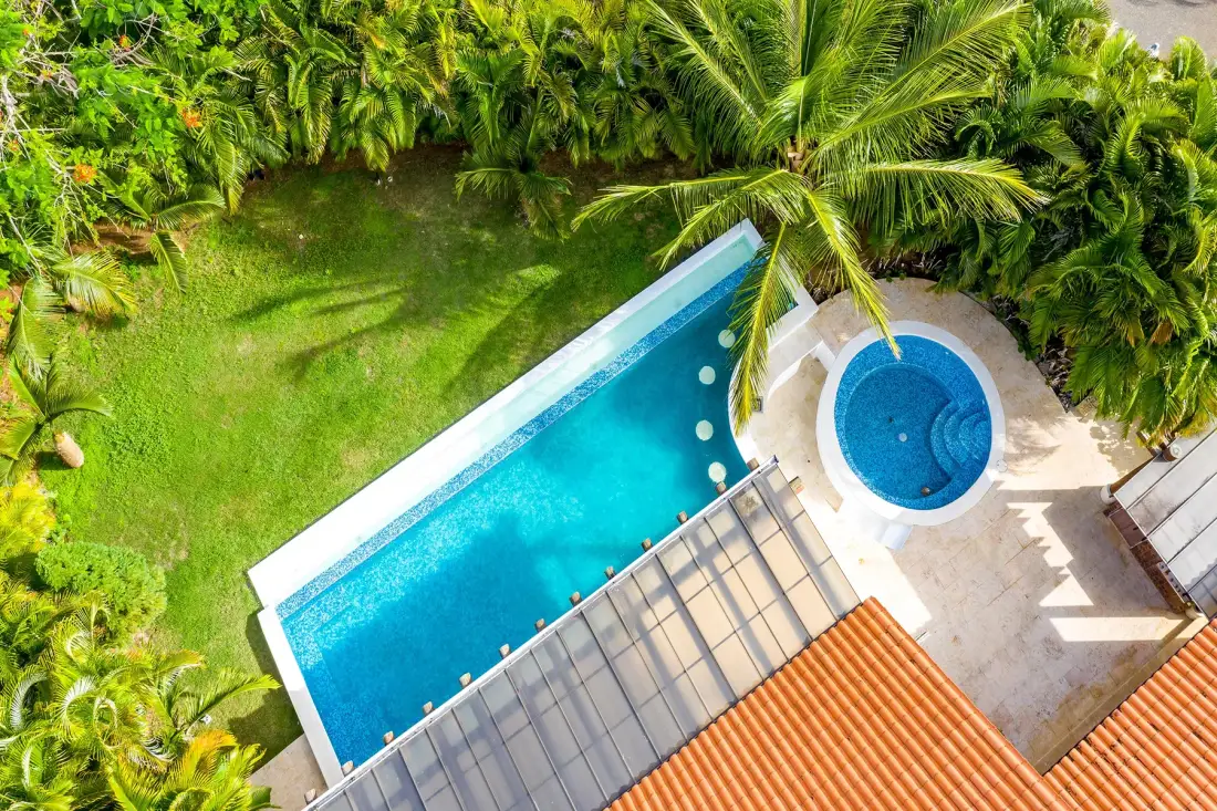Vista aérea de una piscina y un spa circular rodeados de vegetación tropical.