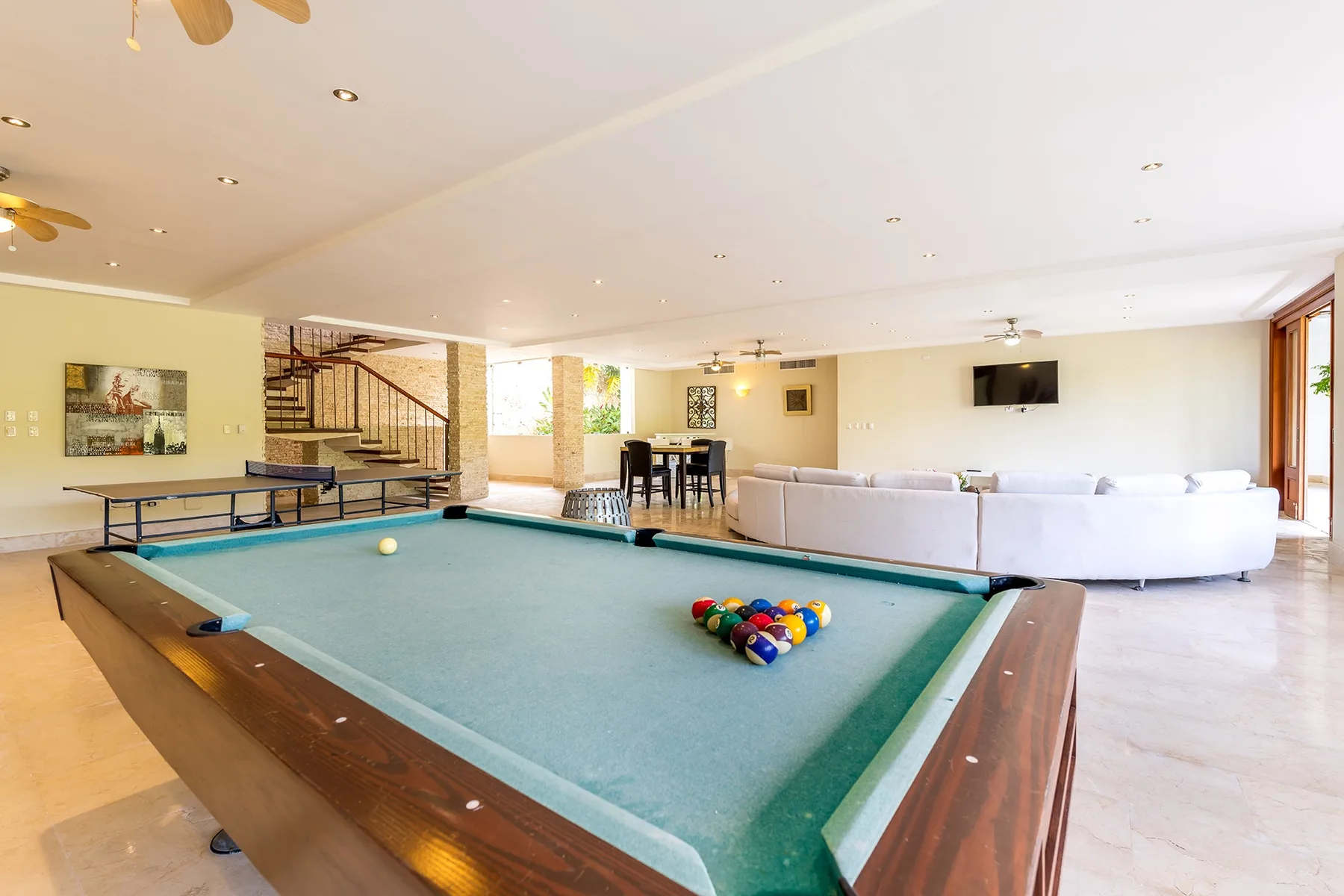 Una sala de recreación con mesa de billar y zona de asientos.