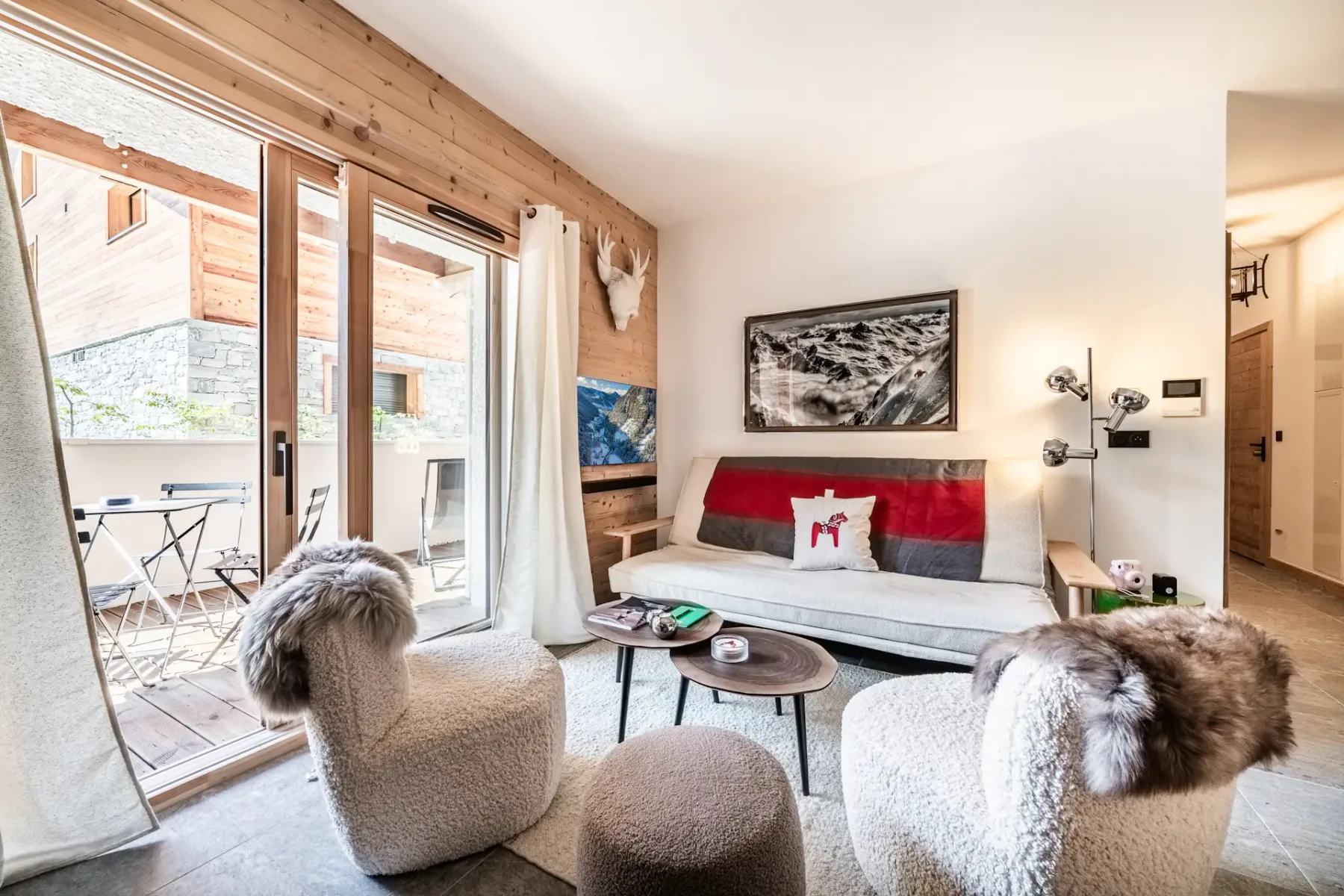 Living area with seating, a coffee table, and glass doors opening to a balcony.
