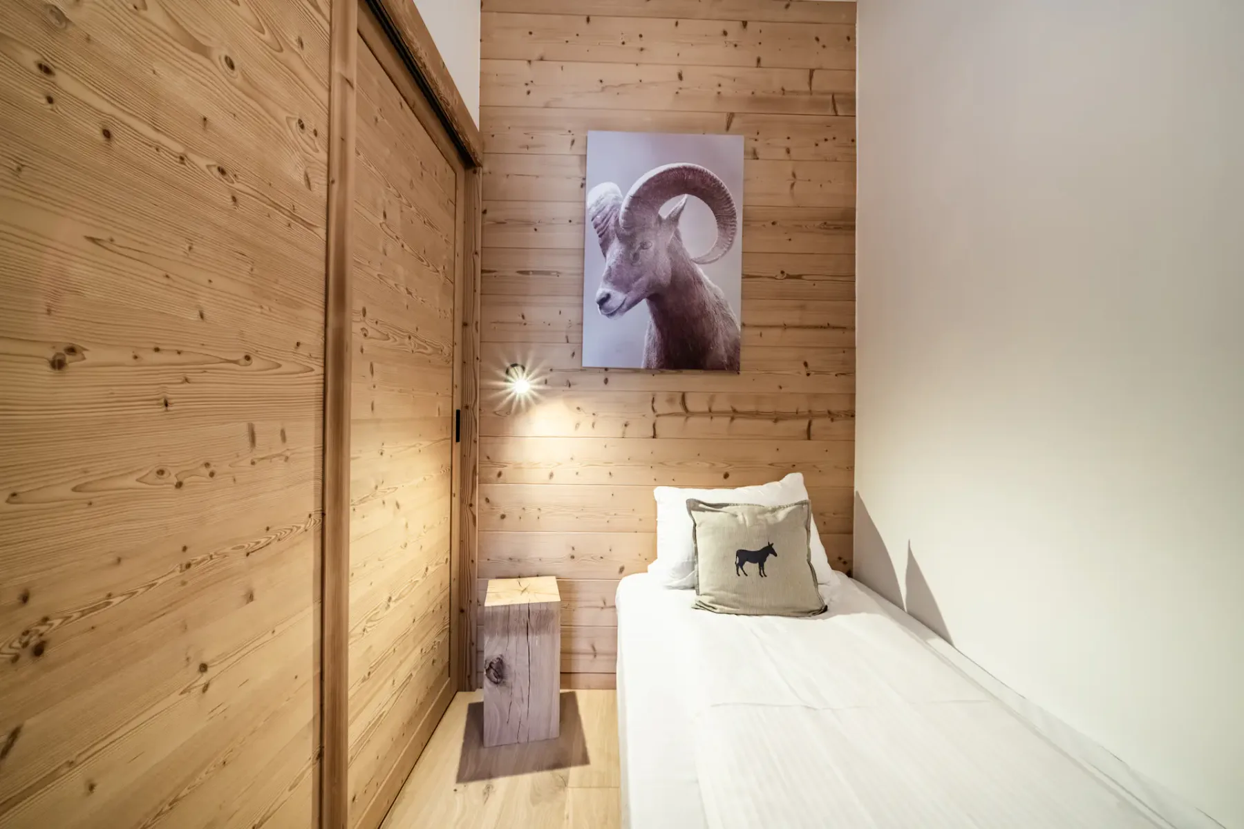 Un dormitorio con una cama individual, paredes revestidas de madera y un cuadro de un animal.