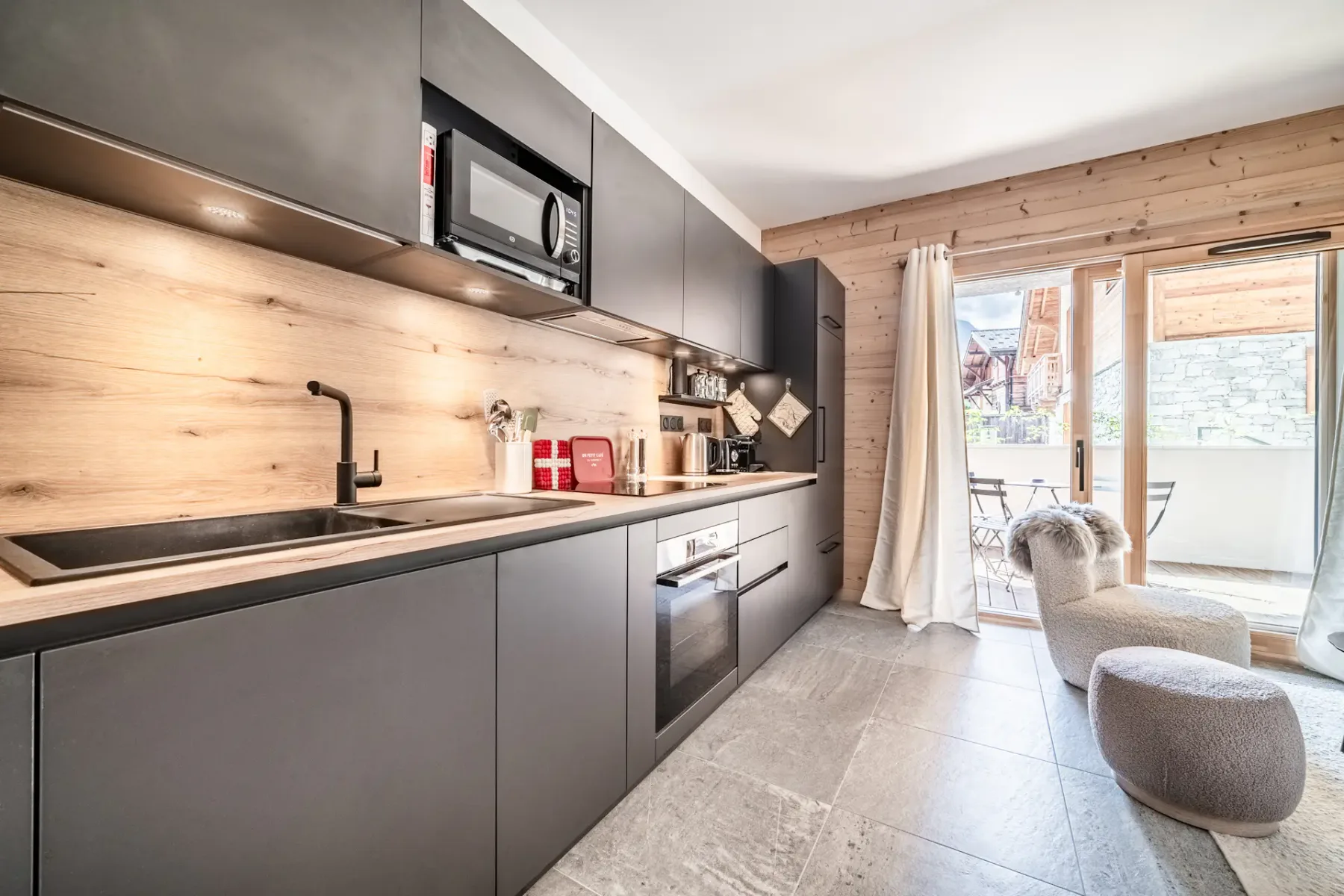 Una cocina moderna se abre a una zona de comedor con mesa y asientos junto a puertas de vidrio.