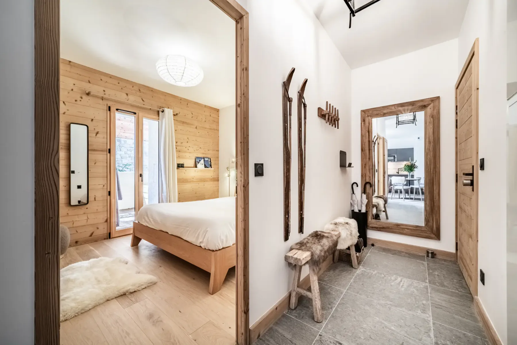 Un pasillo luminoso con suelo gris y vistas a un dormitorio.