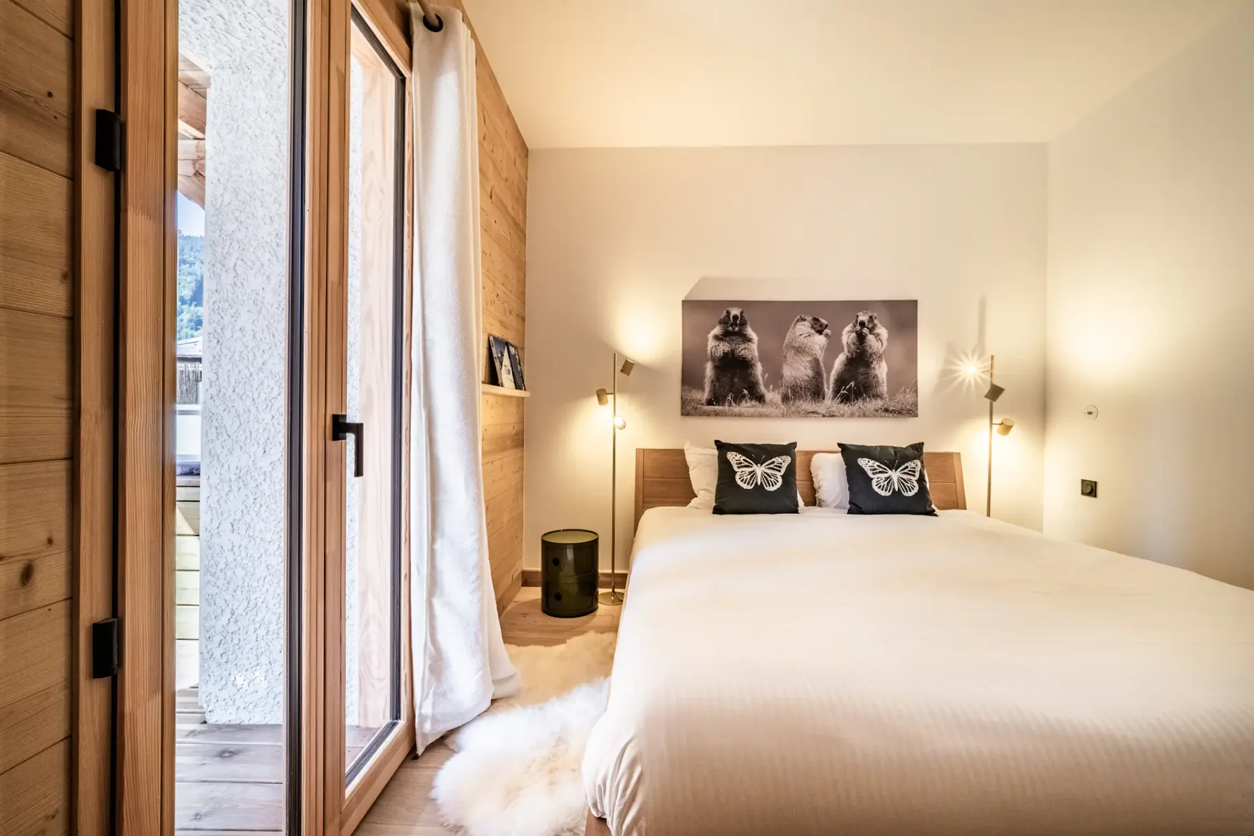Dormitorio con una cama grande, almohadas estampadas y una puerta alta de cristal.