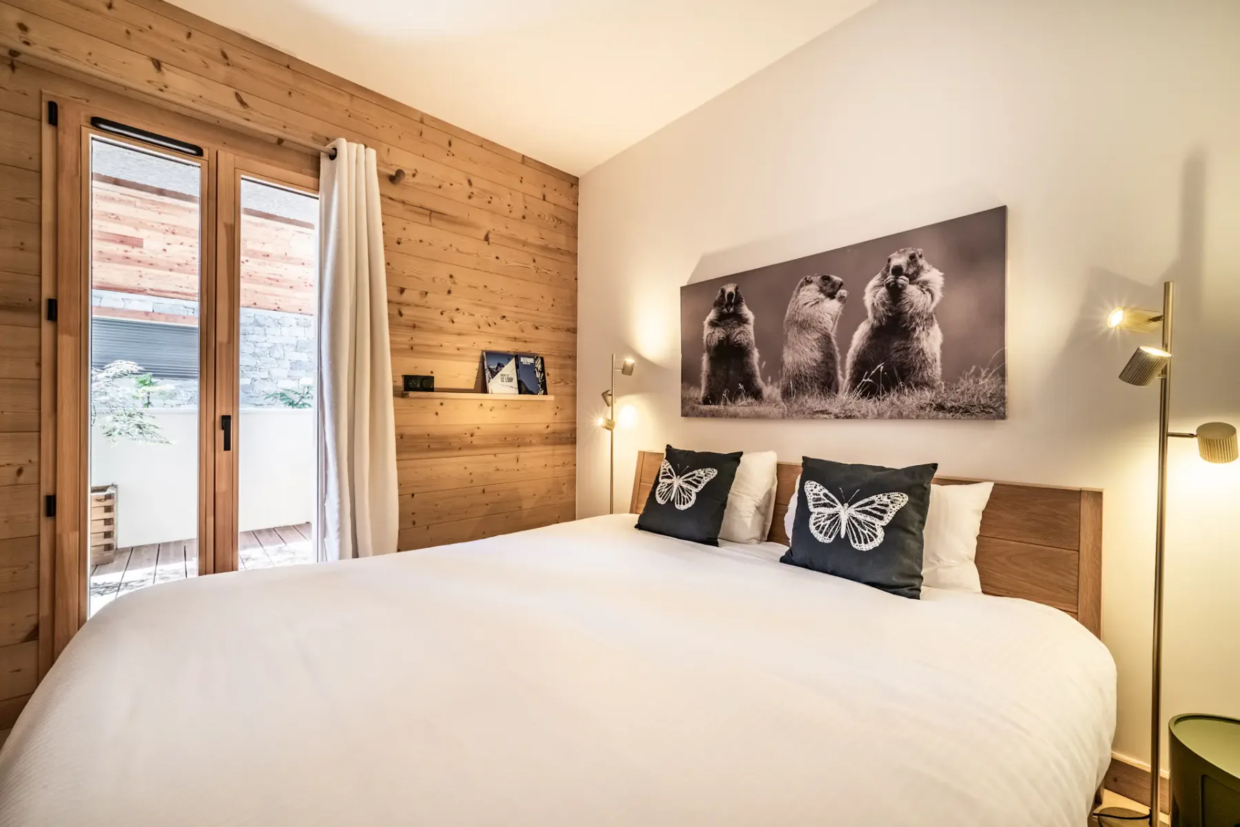Un dormitorio con una cama, almohadas con mariposas y una gran fotografía de animales sobre el cabecero.