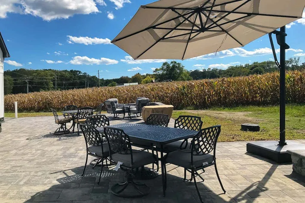 Un patio al aire libre con mesas y sillas bajo una sombrilla grande.