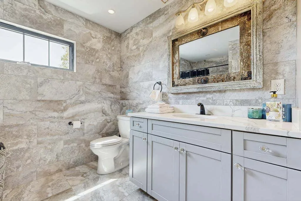 Un baño con un tocador largo, un espejo y una ventana.