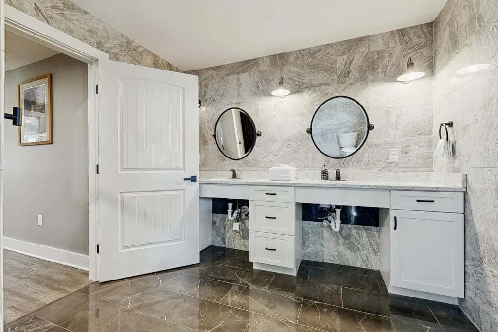 Un tocador de baño con dos espejos redondos y una encimera larga.