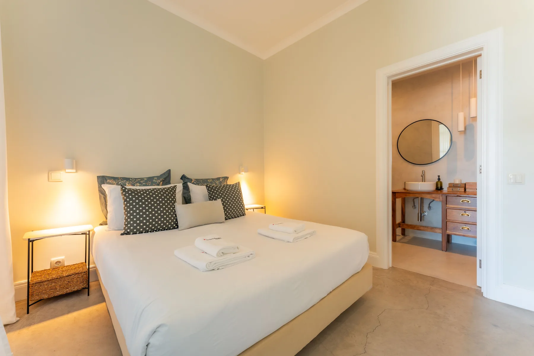 Un dormitorio con una cama bien hecha y una puerta abierta al baño.