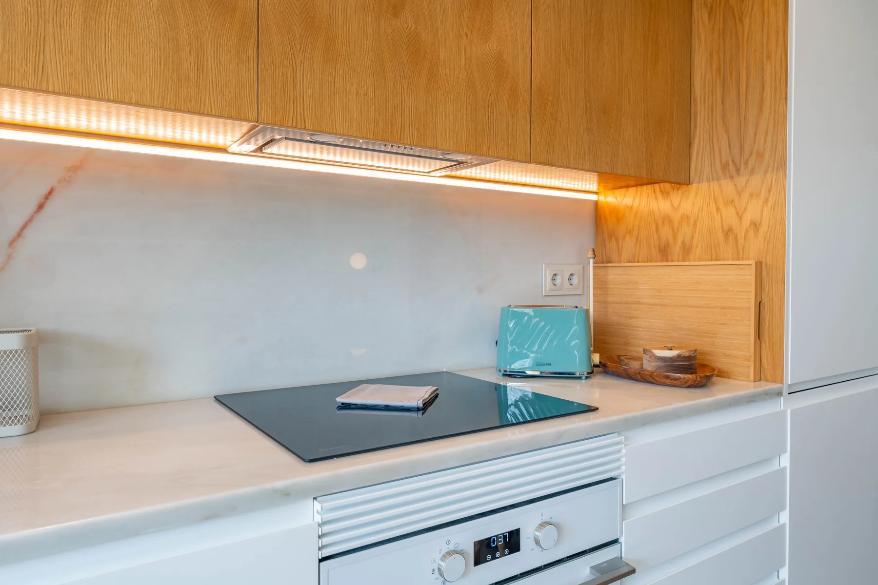 Una encimera de cocina moderna con placa de cocción bajo armarios de madera.