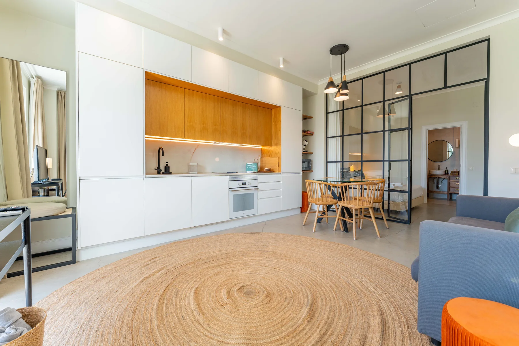 Un estudio diáfano combina una cocina blanca, comedor y zona de estar.