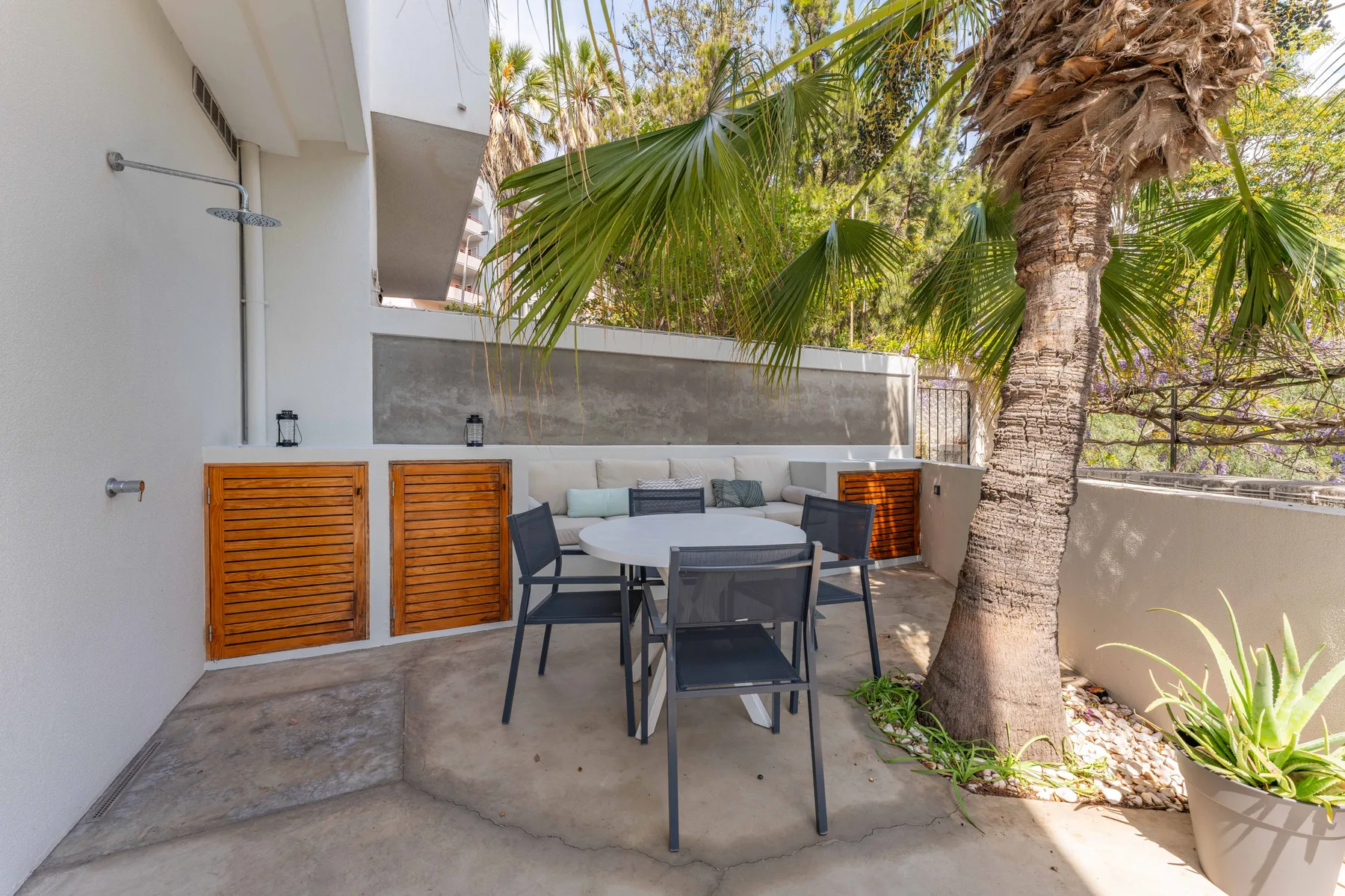 Un patio exterior con una mesa de comedor y palmeras.