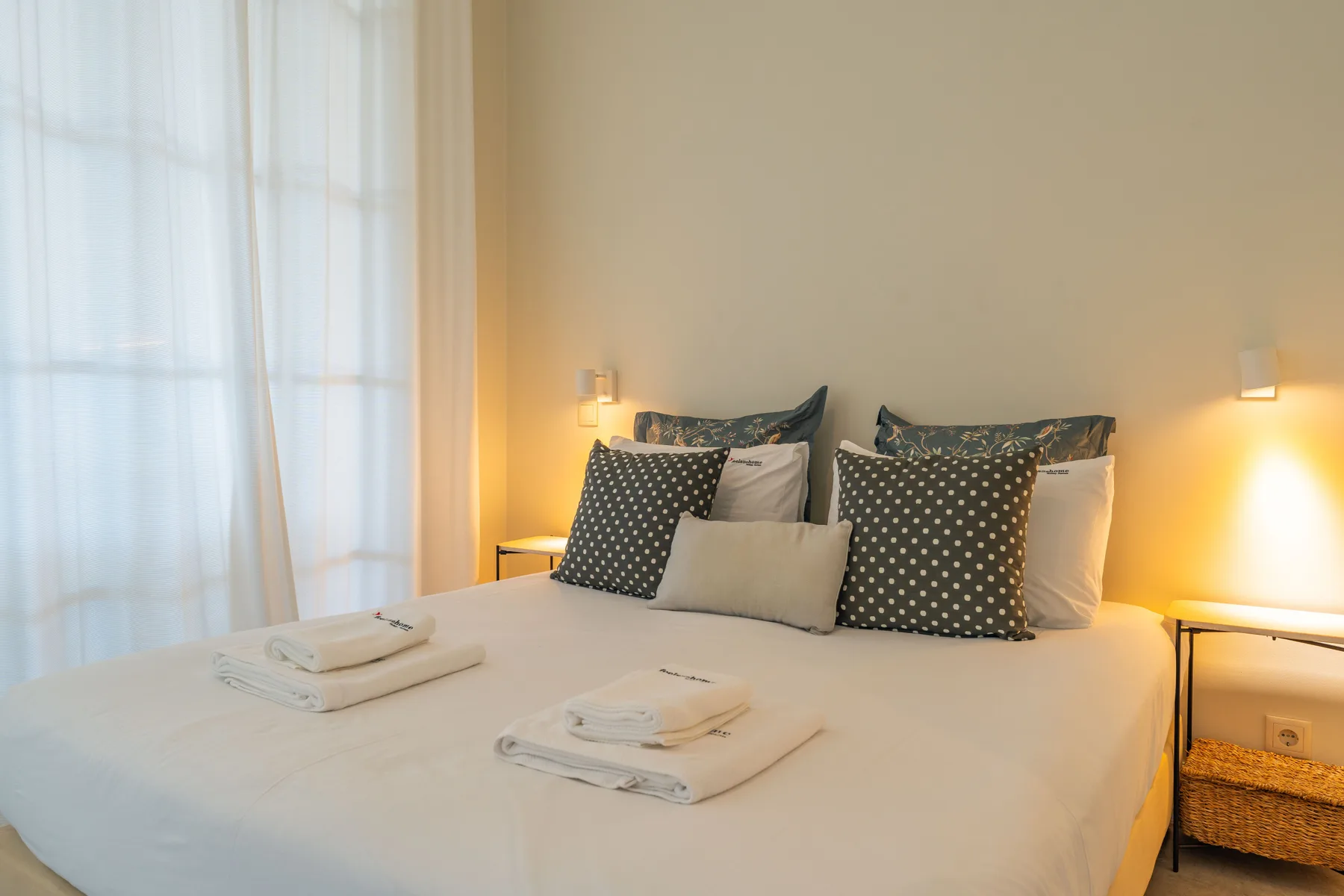 Un dormitorio con una cama bien hecha, toallas dobladas y lámparas de mesilla.
