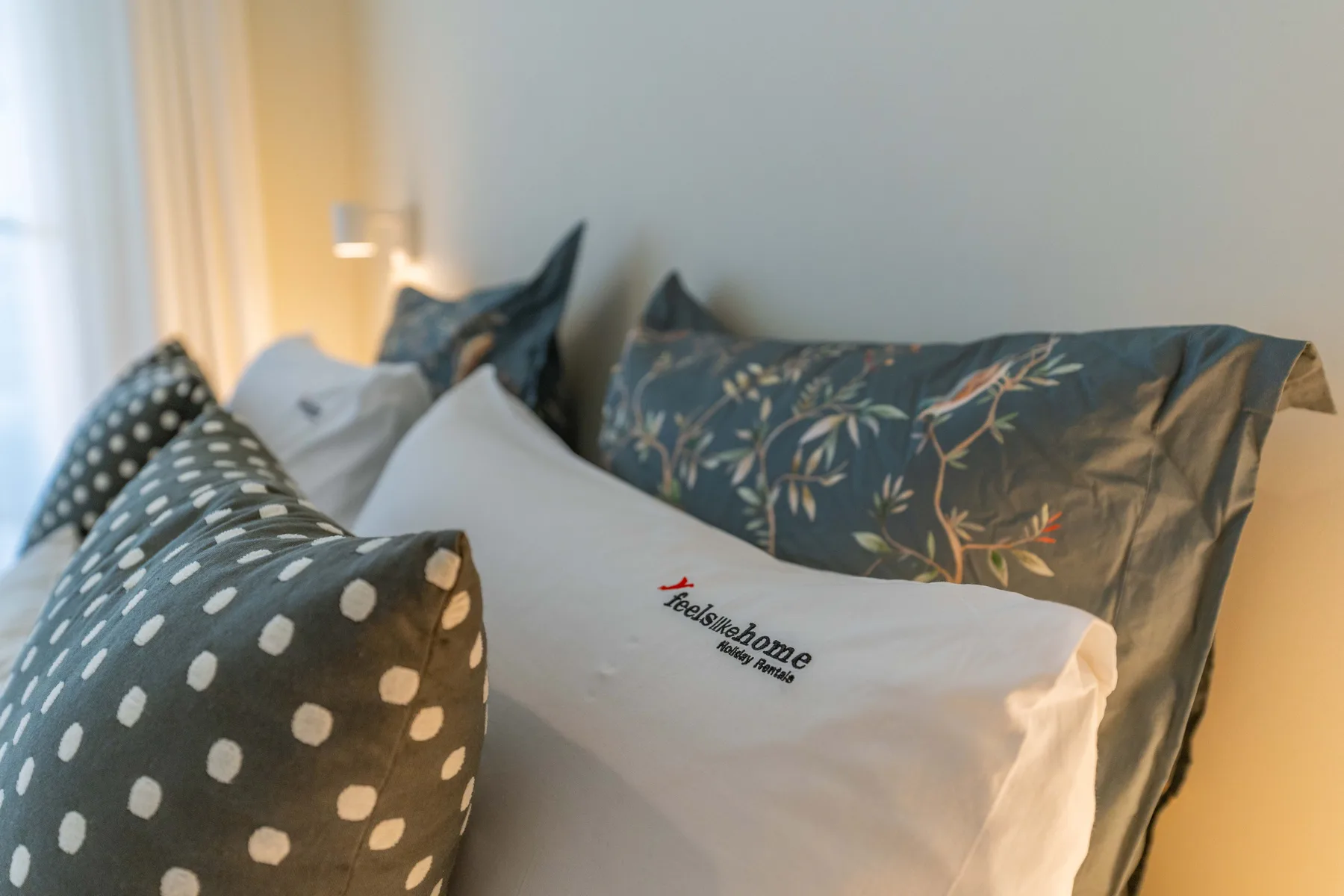 Una cama con almohadas blancas y cojines estampados.