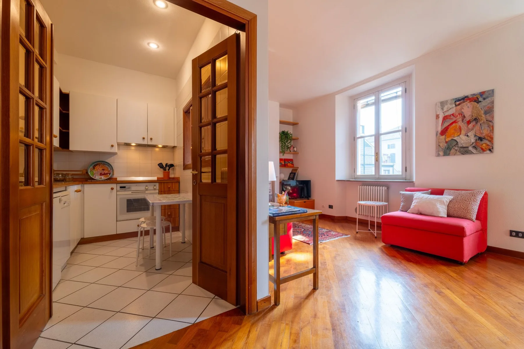 Una luminosa sala de estar con asientos rojos y vista abierta a la cocina.
