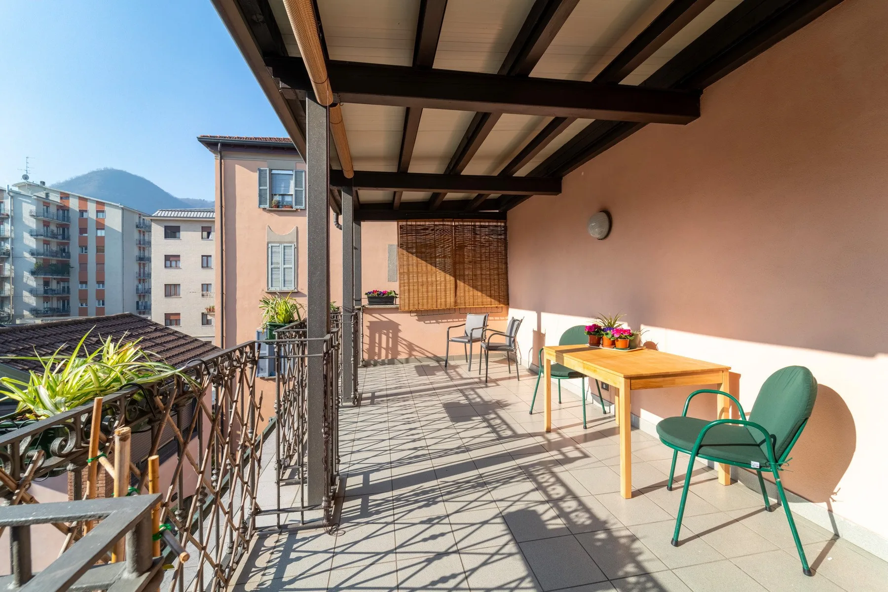 Una terraza cubierta con una mesa y sillas junto a una barandilla metálica.