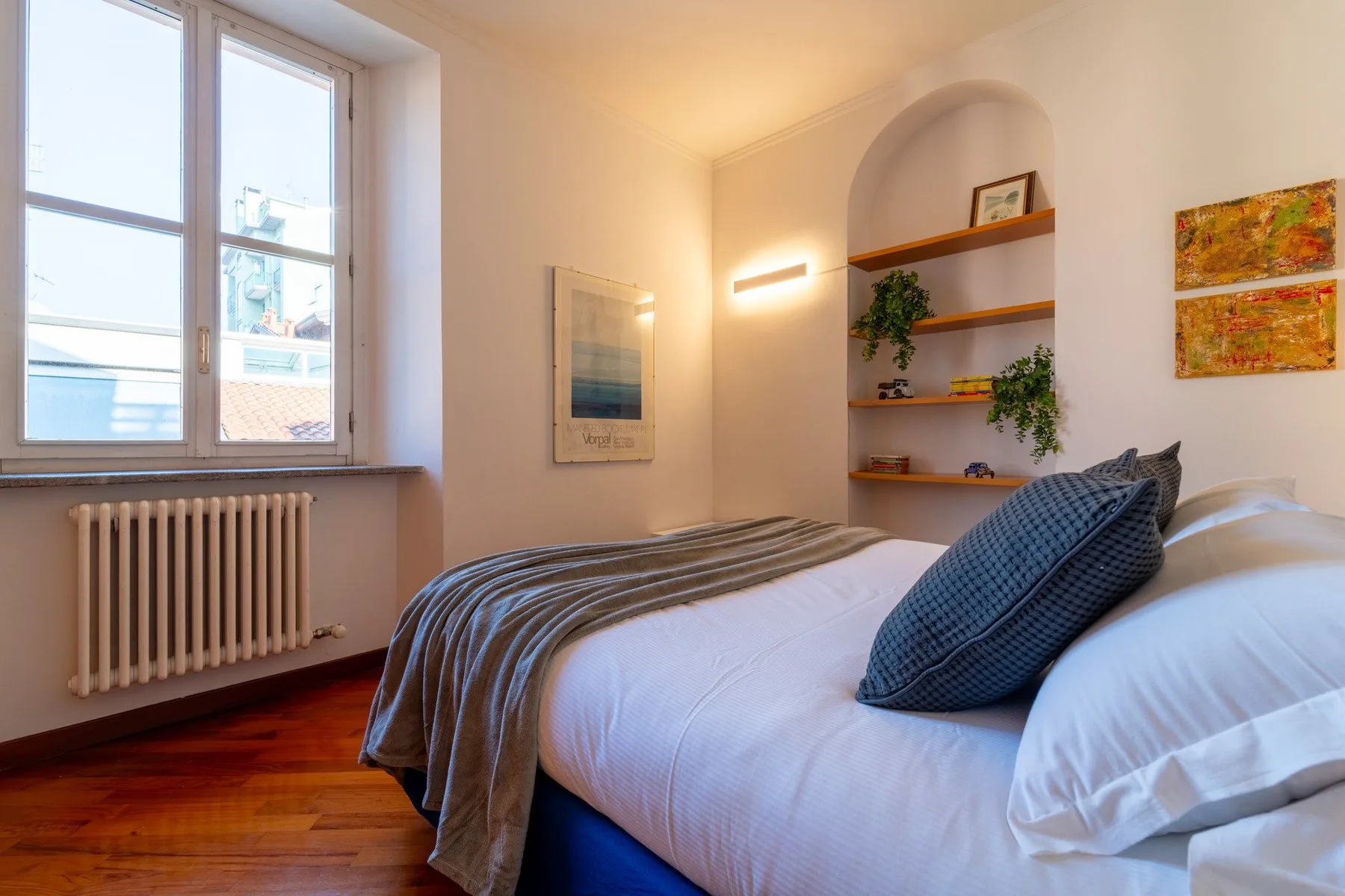 Un dormitorio luminoso con una gran ventana y una cama bien hecha.