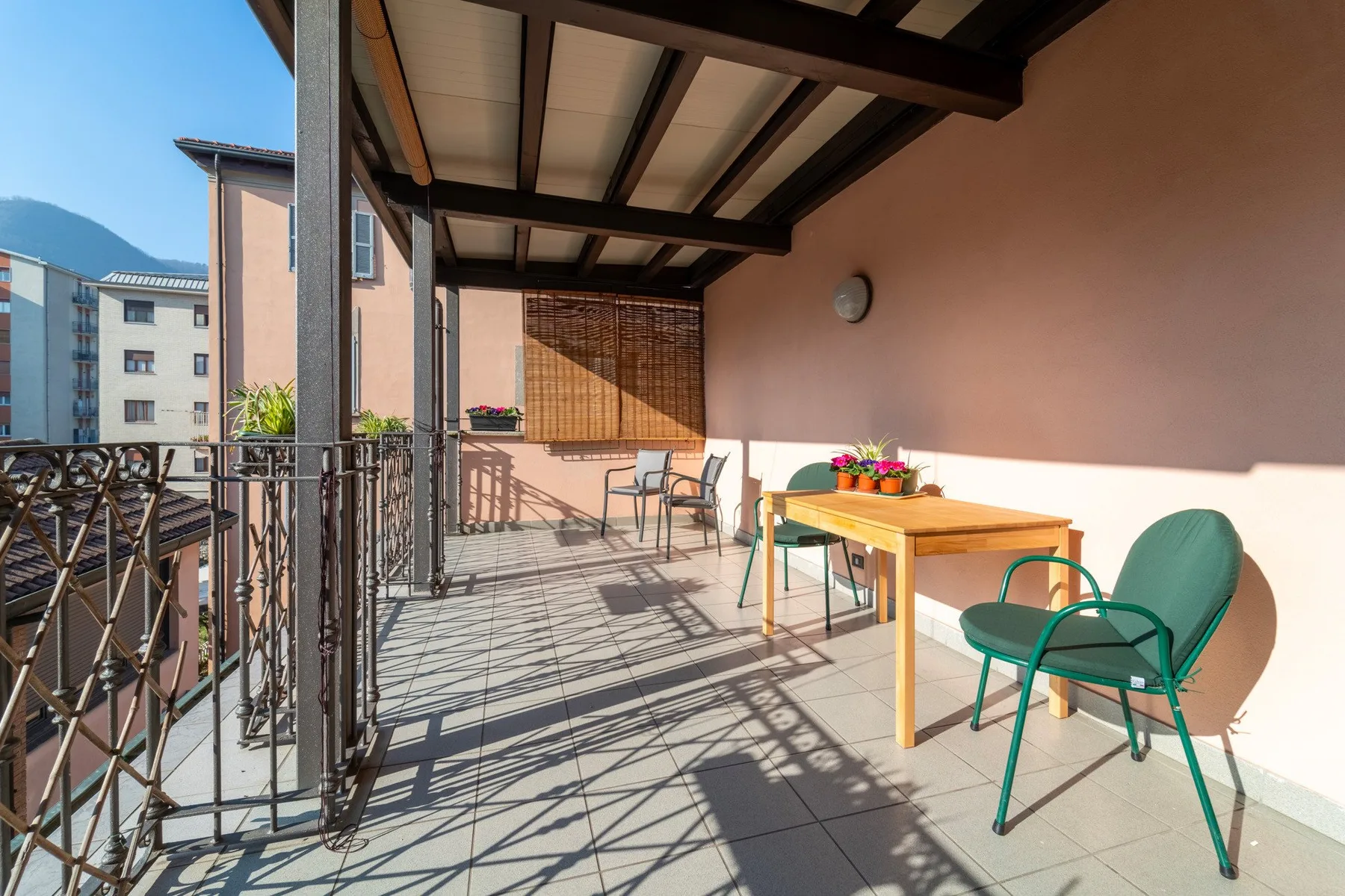 Una terraza cubierta con una mesa y sillas junto a una pared color durazno.