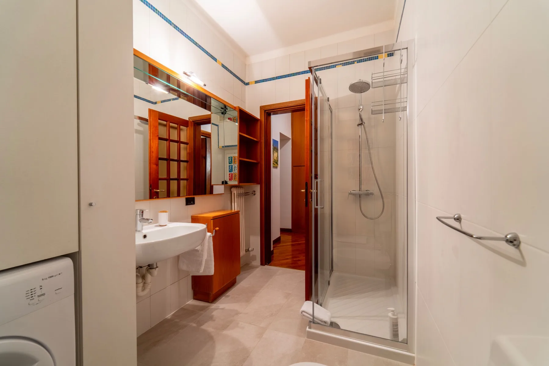 Un baño luminoso con lavabo, tocador y ducha de vidrio.