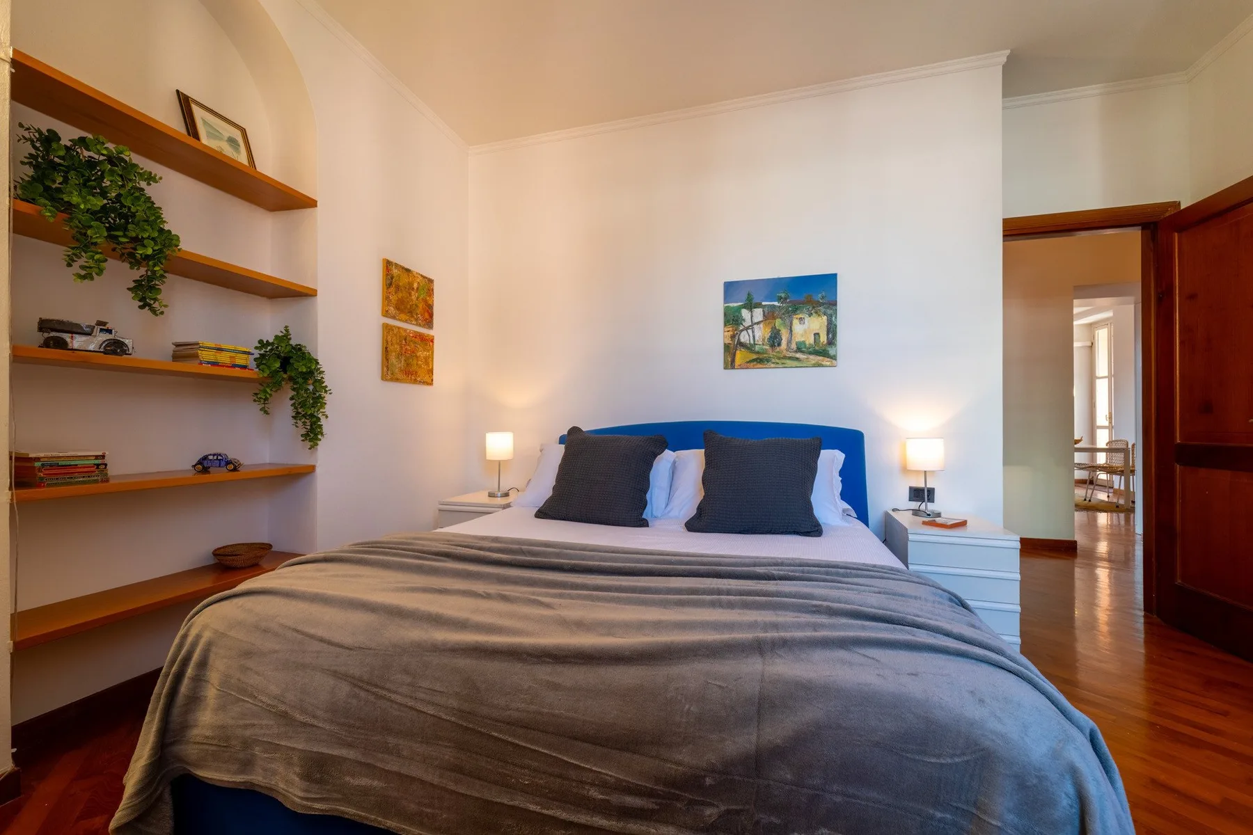 Un dormitorio con una cama, mesitas de noche y estantes empotrados.