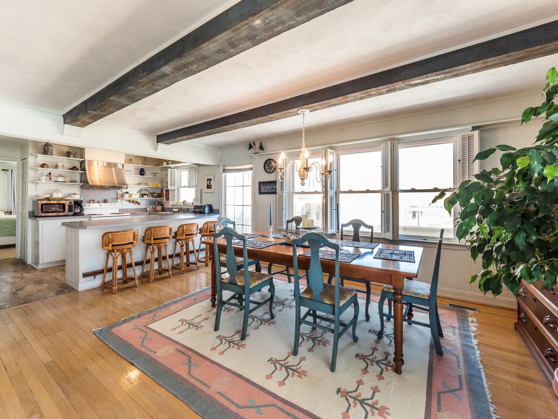 Una cocina abierta y comedor con una mesa de madera junto a grandes ventanas.