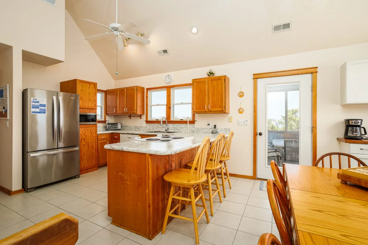 Una cocina luminosa con gabinetes de madera, una isla central y una mesa de comedor.