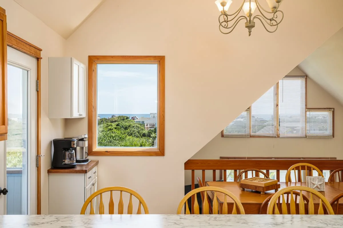 Comedor con asientos de madera y una ventana con vistas a la vegetación.