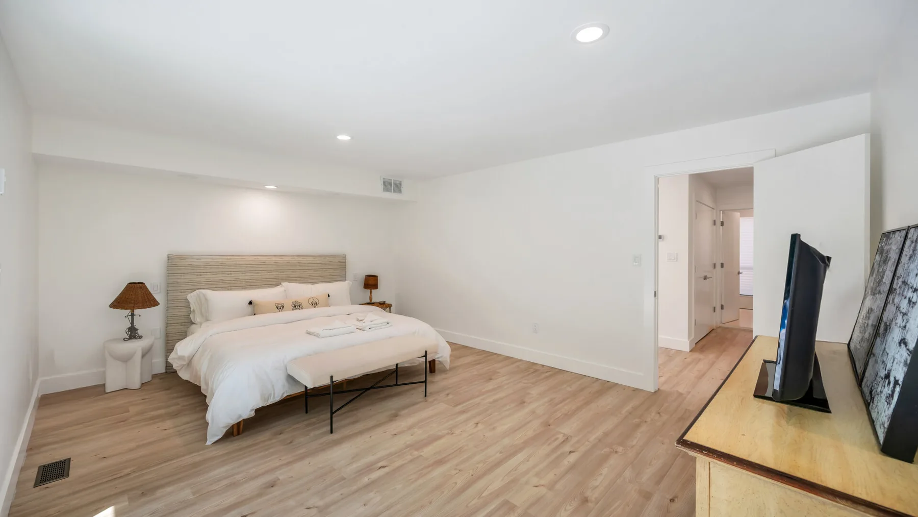 A bright bedroom with a bed and a television on a wooden dresser.
