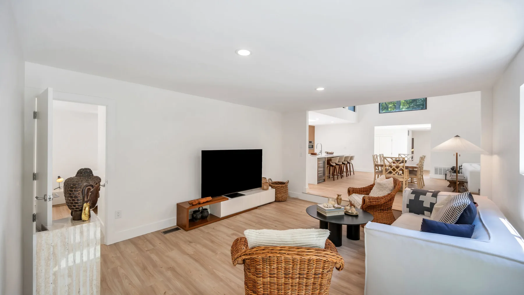 A bright living room with a television, seating, and an adjoining dining area.