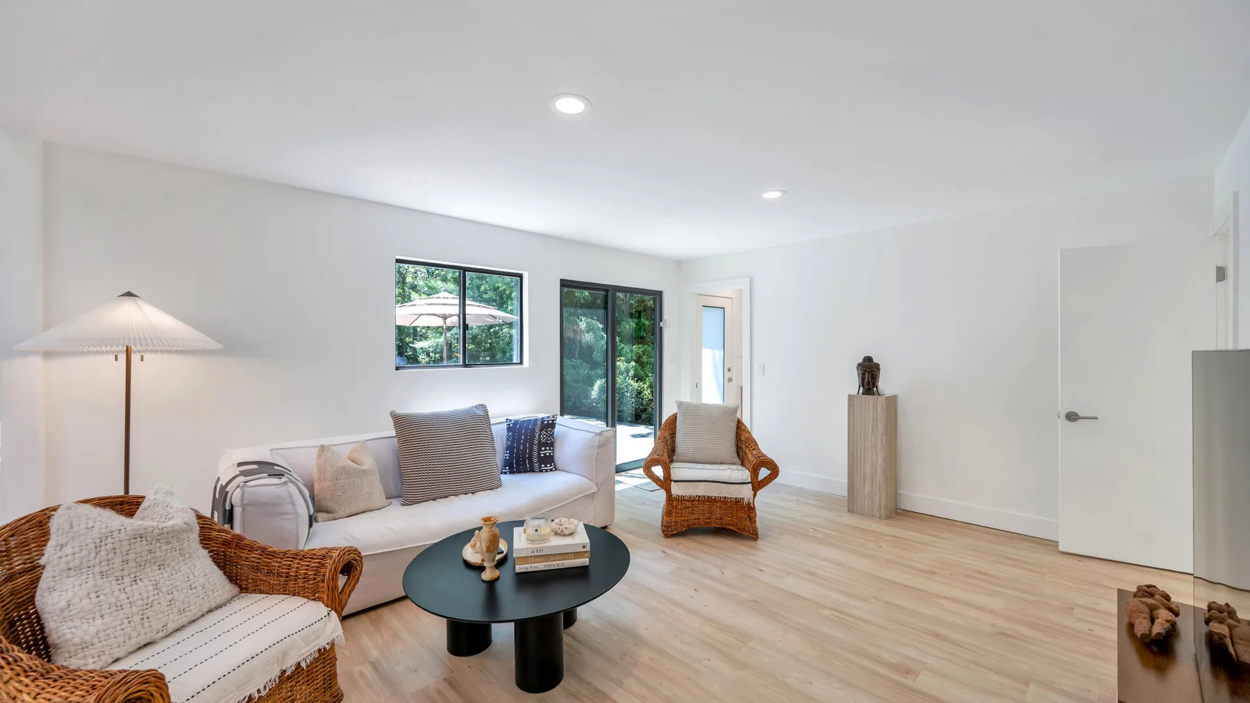 A bright living room with seating, a round coffee table, and large windows.