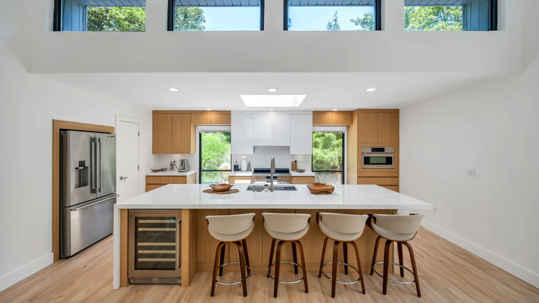A bright kitchen with a large island, bar seating, and wide windows.