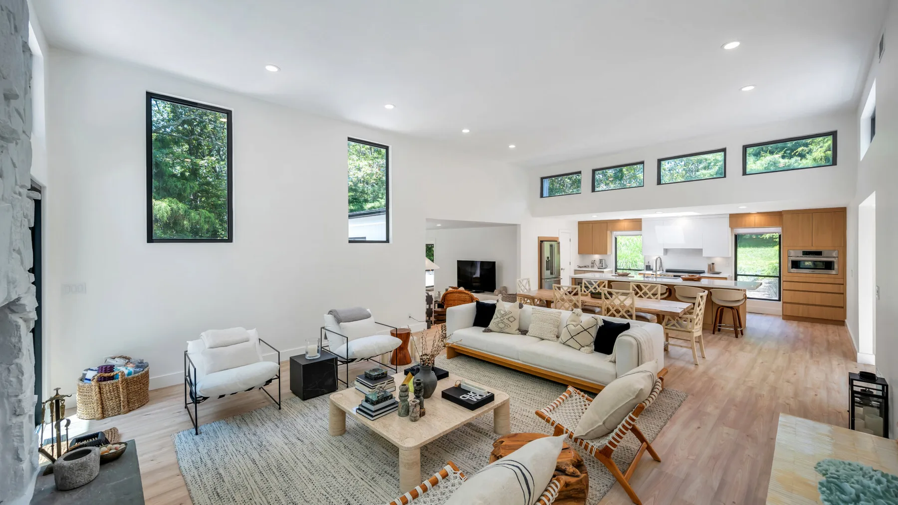 A bright open-plan living and dining room with seating, a table, and large windows.