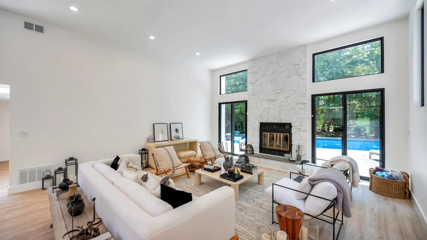 A bright living room with seating arranged around a fireplace and large windows.