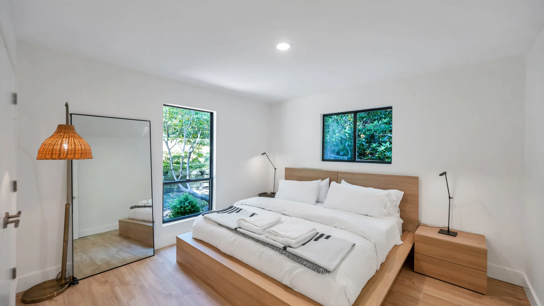 A bright bedroom with a large bed and windows overlooking greenery.