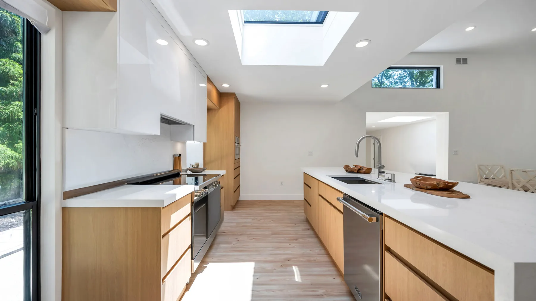 A bright modern kitchen with wood cabinetry and a long white island.