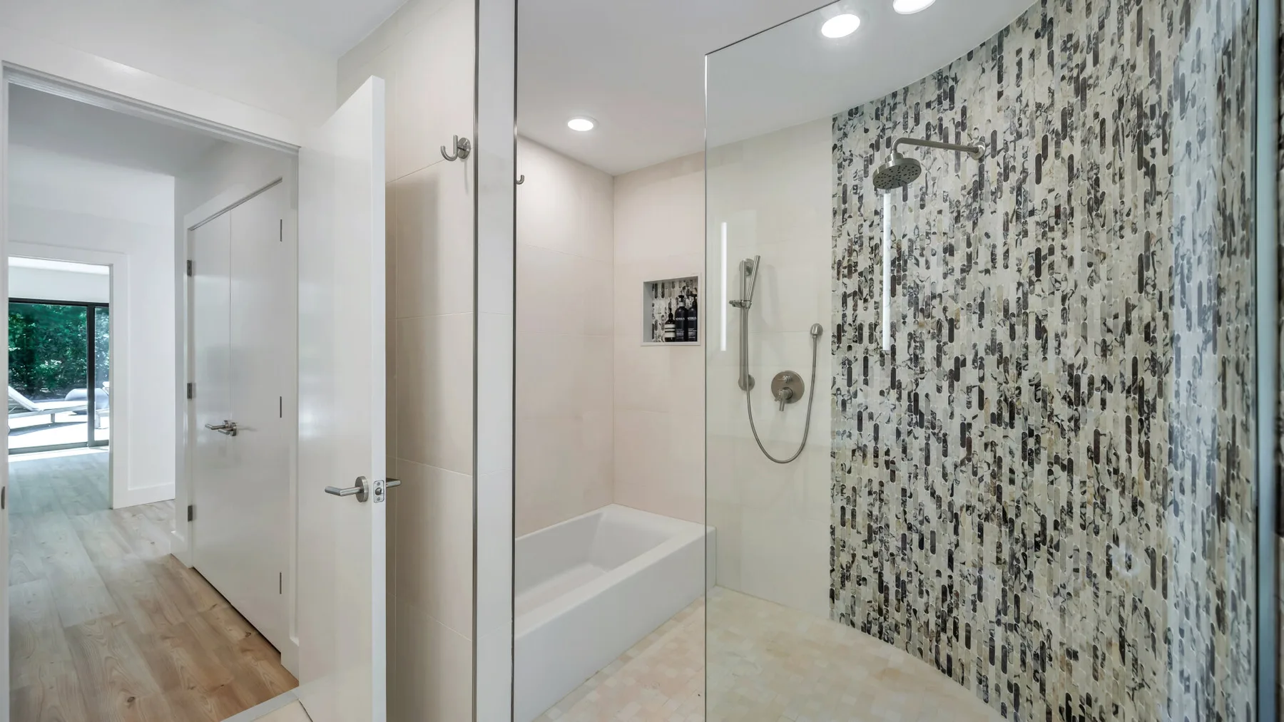 A bathroom with a bathtub, shower, and patterned tile wall.