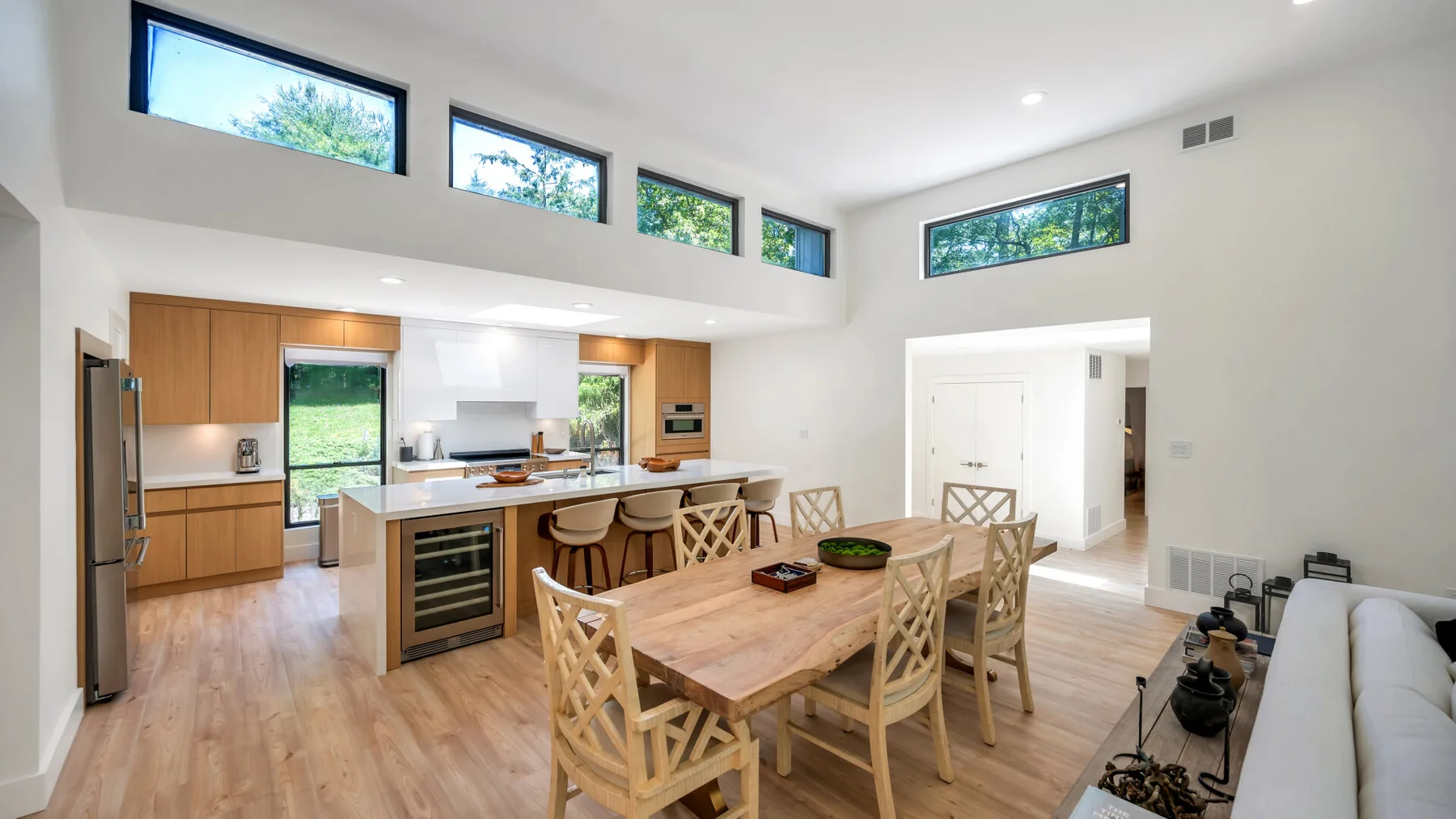 An open-plan kitchen and dining area with a wooden table and high windows.