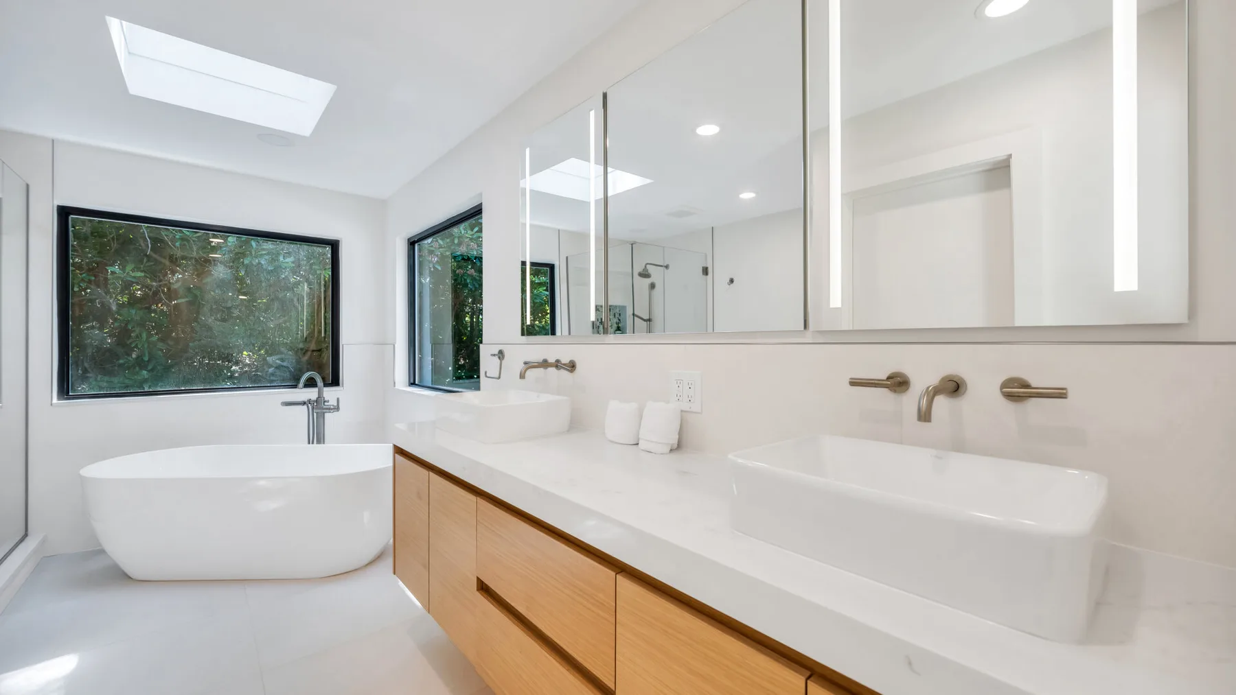 A bright bathroom with a bathtub, double sinks, and a large mirror.