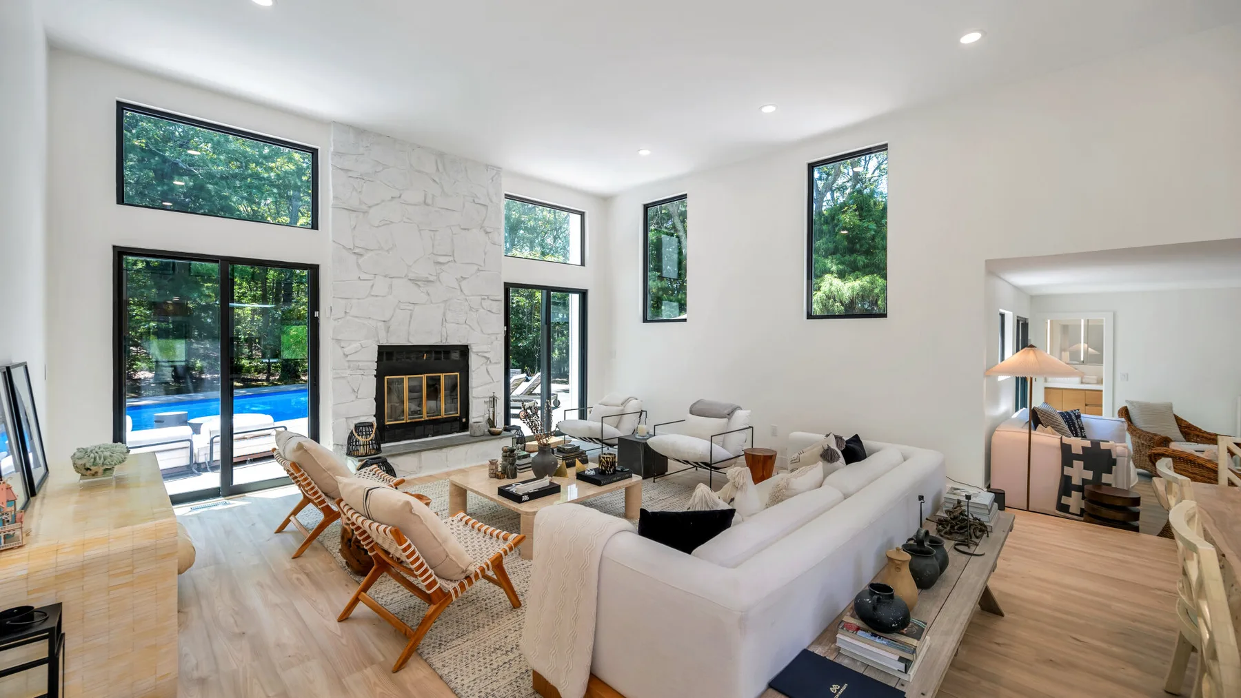 A bright living room with seating arranged around a fireplace and large windows.